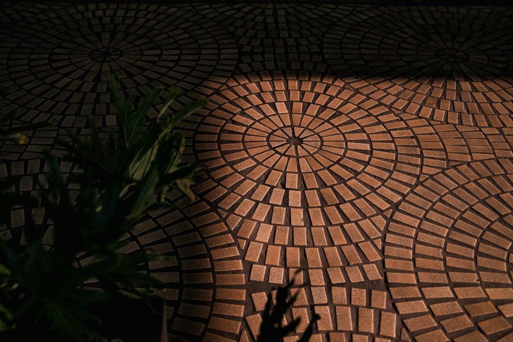 Circular brick pavers are partially illuminated by sunlight.