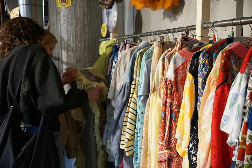 A woman browsing colorful clothes on a rack.