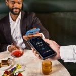 Man paying with phone at restaurant table