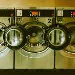 a row of washers in front of a row of dryers