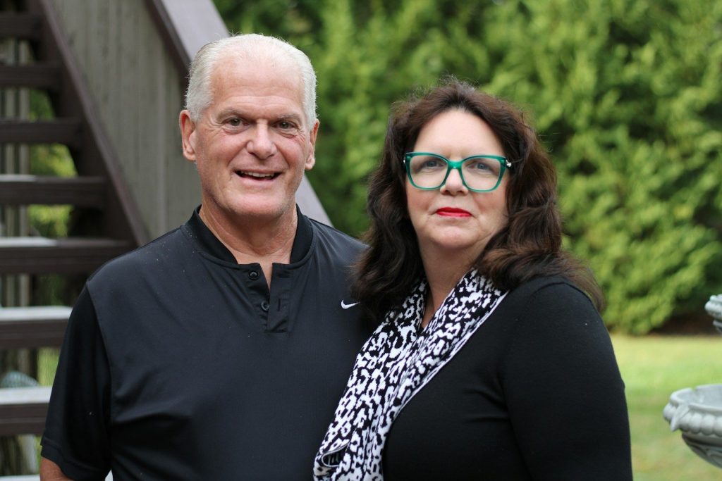 A smiling couple standing outdoors near stairs.