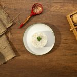 A mound of white rice with a green garnish.