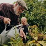 a man and a child looking at a plant