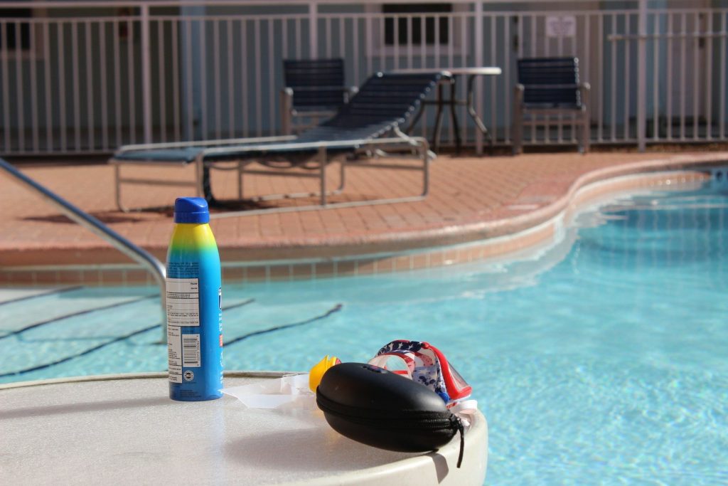 a bottle of sunscreen next to a swimming pool