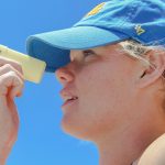 a woman wearing a blue hat looking through a magnifying glass