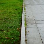 green grass field near gray concrete pathway