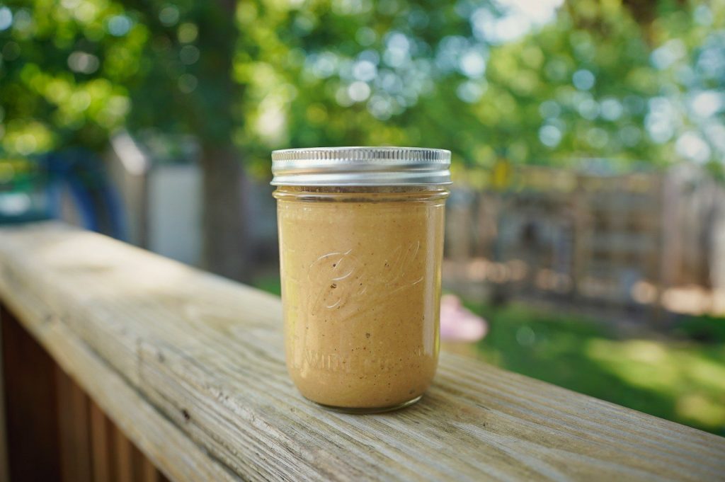 A jar of peanut butter sitting on top of a wooden fence