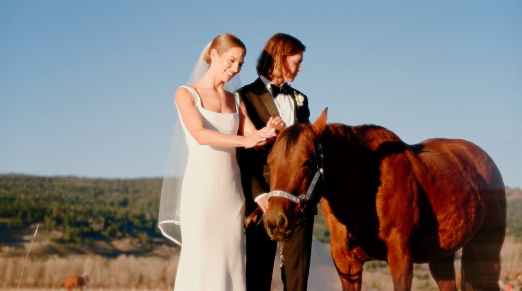 a bride and groom standing next to a horse