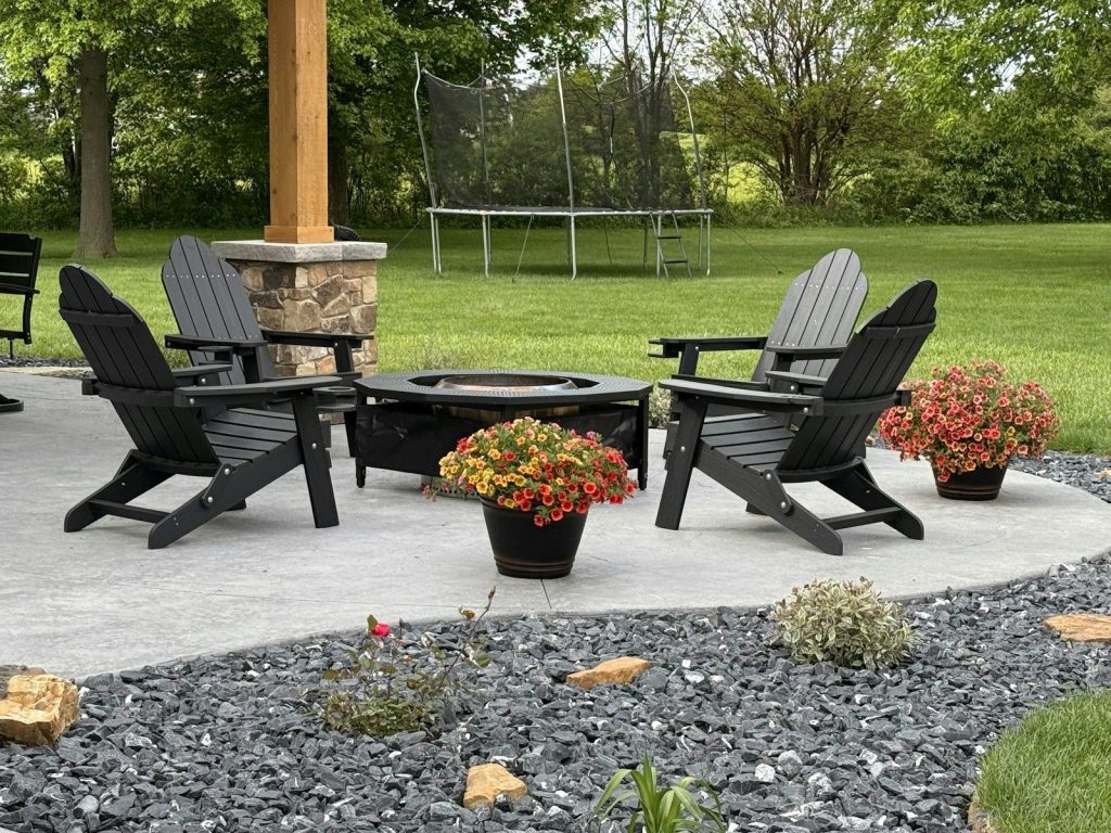 Backyard patio with adirondack chairs, fire pit, and flowers.