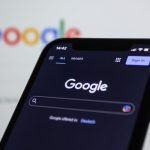 a close up of a cell phone with the google logo in the background