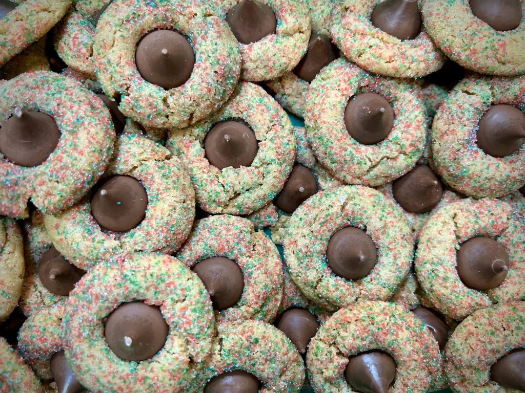Many colorful sprinkle cookies with chocolate kisses.