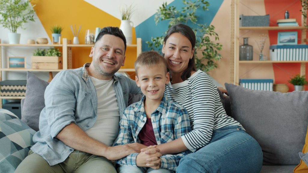 A happy family of three sitting on a couch.