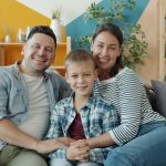 A happy family of three sitting on a couch.