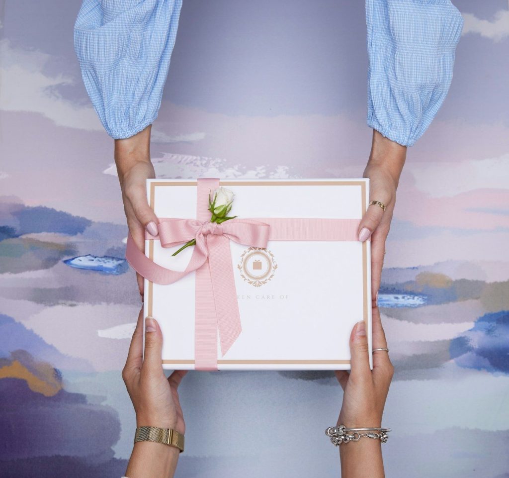 Two hands exchanging a beautifully wrapped gift box.