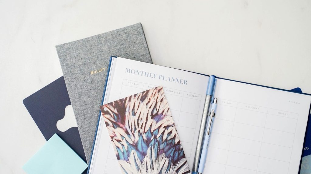 a notebook with a planner and pen on top of it
