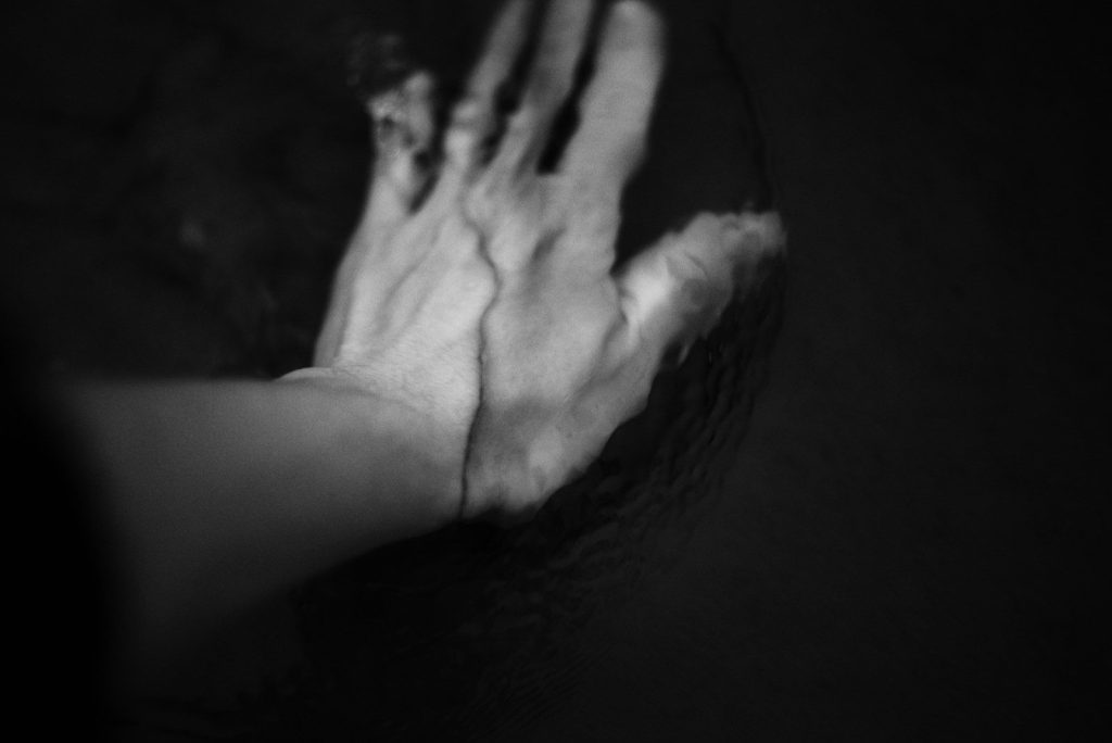 A hand reaching into dark water