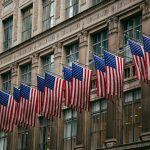 American flags hang in a row on a building.