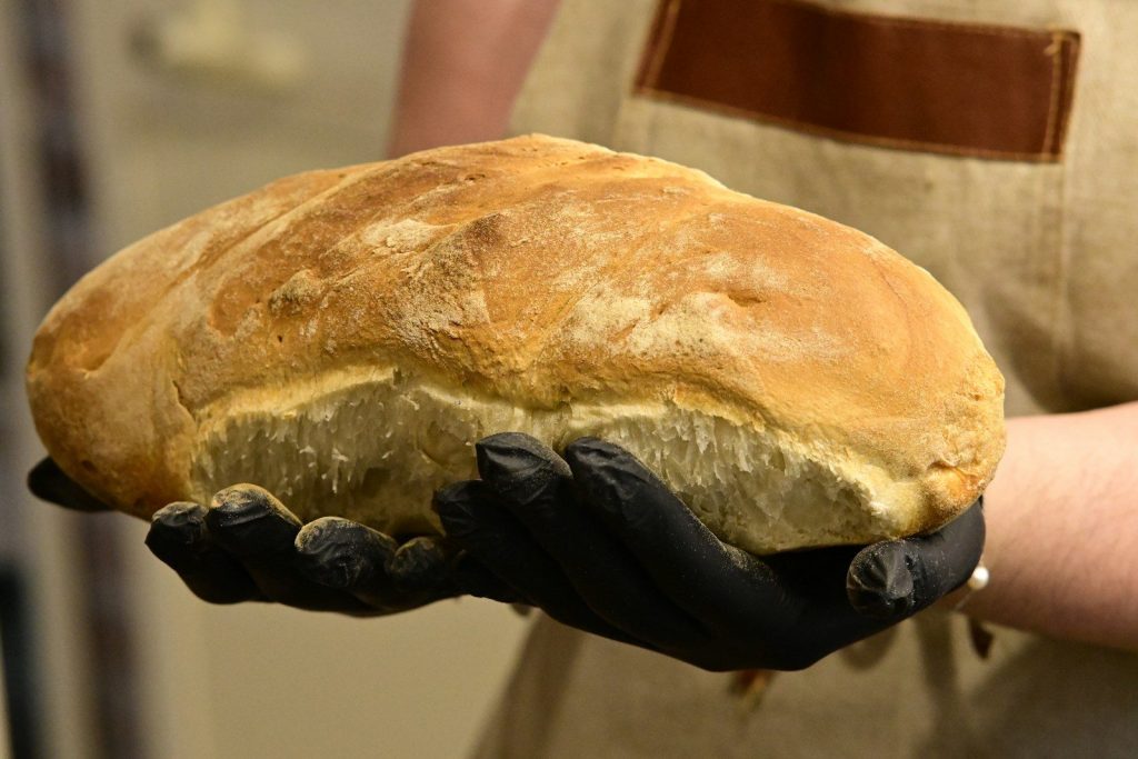 Person holding a freshly baked loaf of bread.