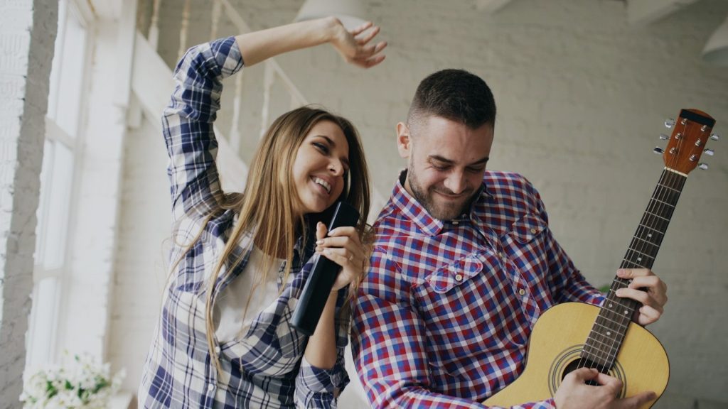 Couple singing and playing guitar together at home