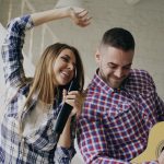 Couple singing and playing guitar together at home
