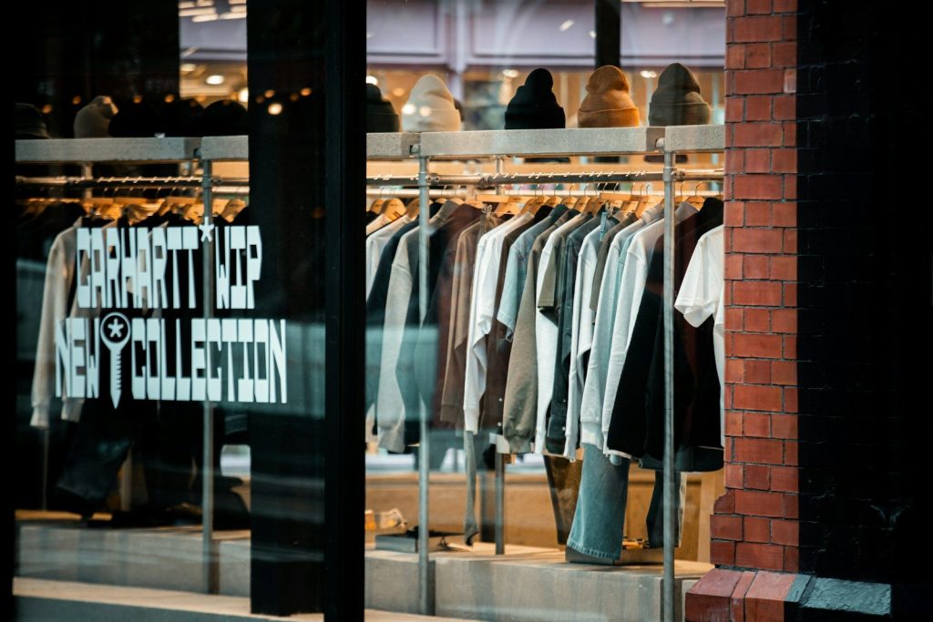 Clothes displayed on racks inside a store window.