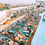 people lying on blue and white lounge chairs