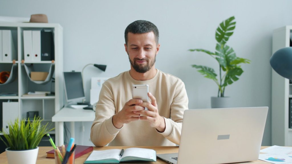 Man smiling while looking at his smartphone at his phone.