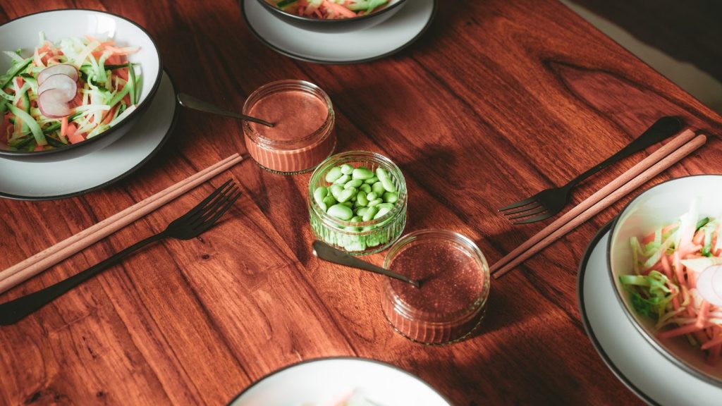 A wooden table topped with plates and bowls of food