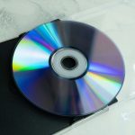 A shiny cd reflecting rainbow colors on a surface.