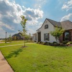 white and brown house near green grass field under white clouds and blue sky during daytime
