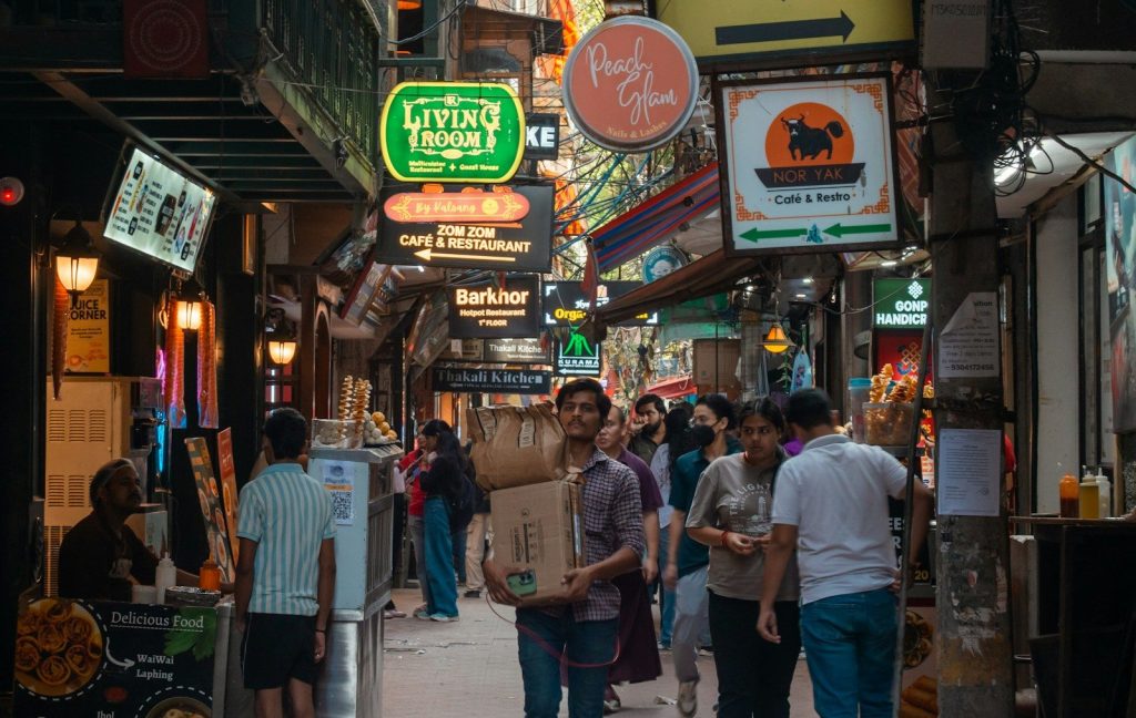 Crowded street market with many signs and people.