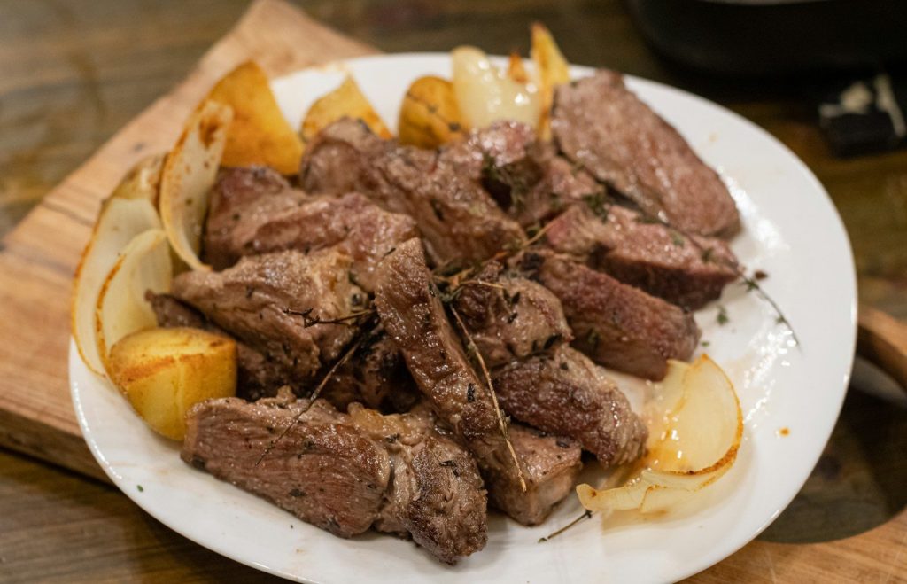 a white plate topped with meat and potatoes
