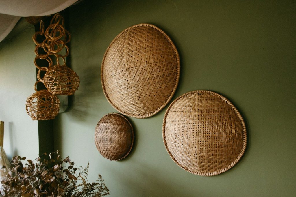 Woven straw baskets hang on a green wall.