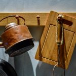 A vintage kettle and cutting board hang on hooks.