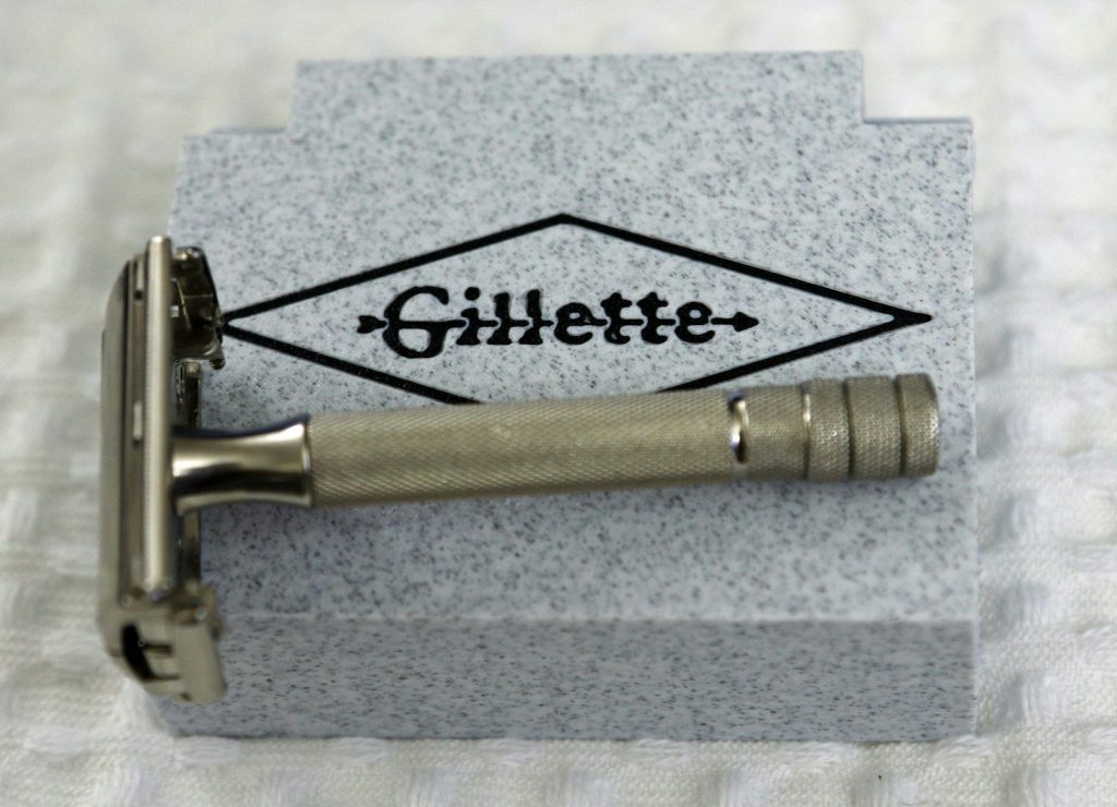 A vintage gillette safety razor rests on a grey box.