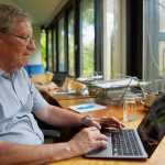 a man sitting at a table using a laptop computer