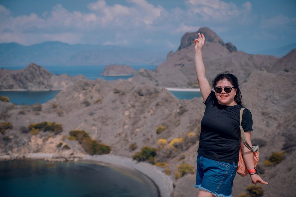 a woman with her arms in the air on top of a mountain