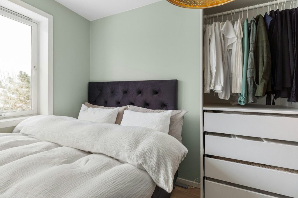 A bedroom with a bed, dresser, and closet