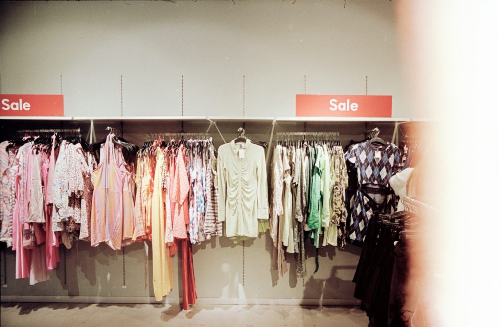 a rack of clothes with a sale sign in the background