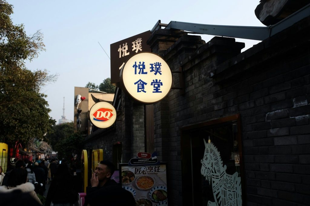 Street signs illuminate a brick building at dusk.
