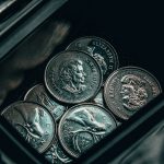 silver round coin on black surface