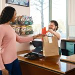 Customer receives a takeout bag from cashier.