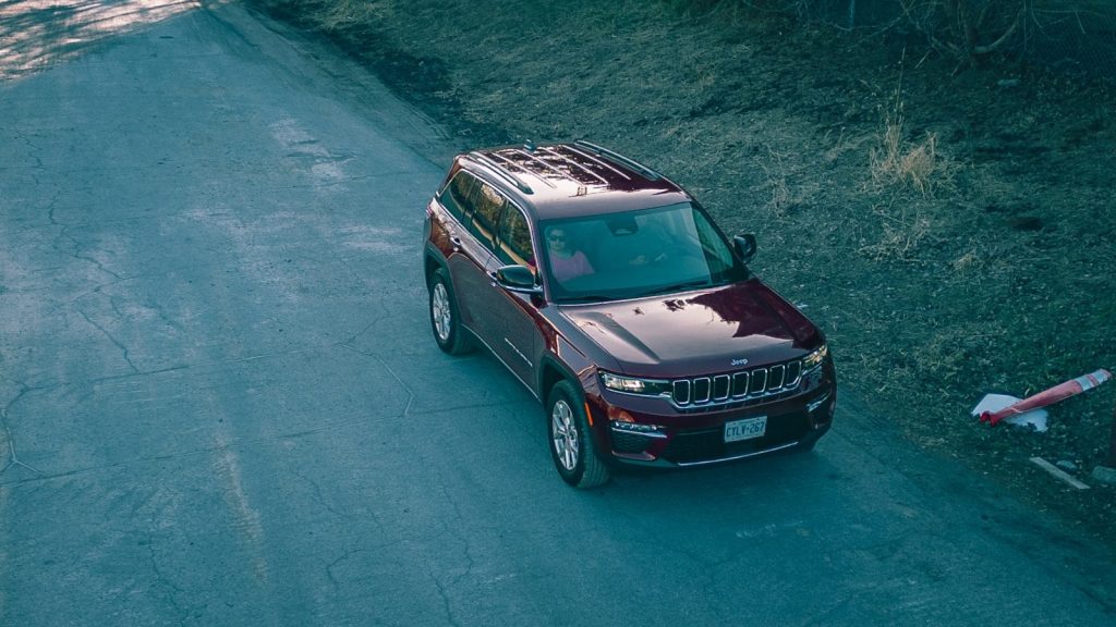 A jeep driving down a road next to a forest