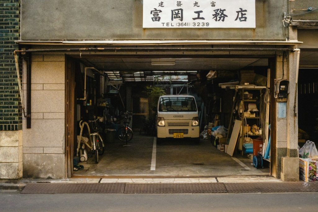 Small white van parked inside a garage workshop entrance