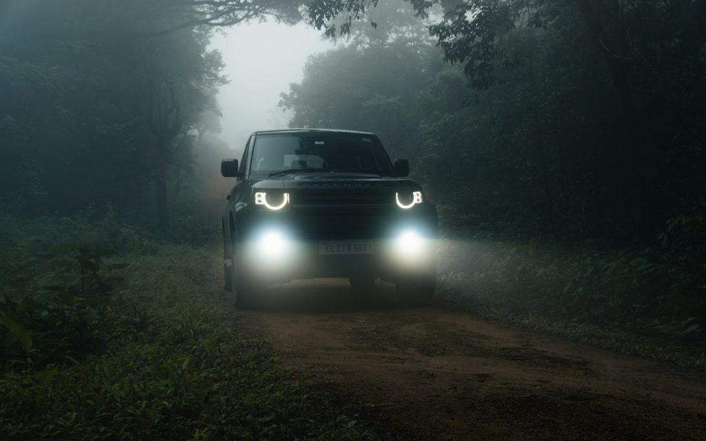 A truck driving down a dirt road in the dark