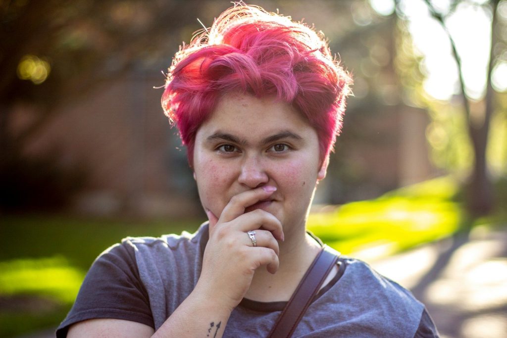 a woman with pink hair and a ring on her finger