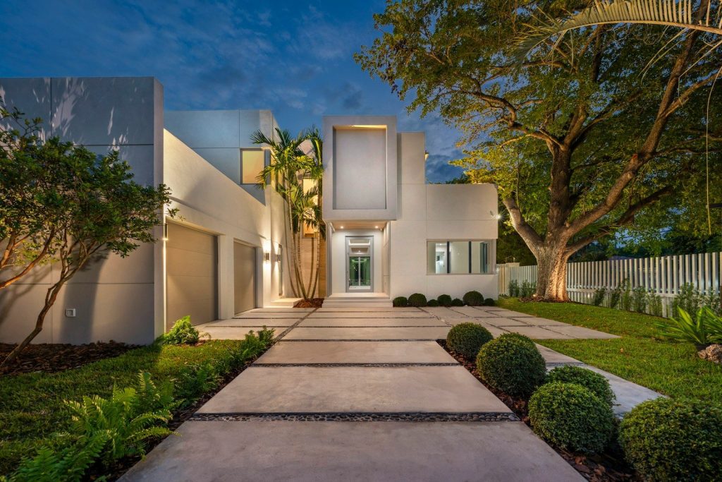 Modern white house with illuminated pathway at dusk