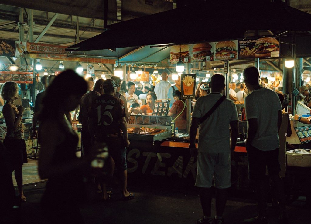 A group of people standing around a food stand