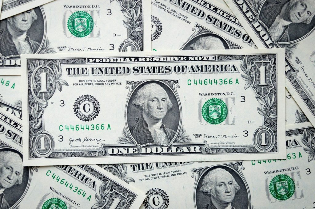 a pile of one dollar bills laying on top of each other