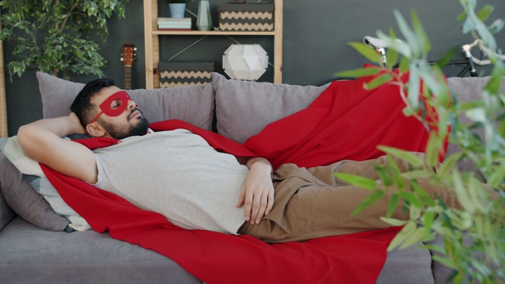 Man in superhero costume sleeping on sofa.